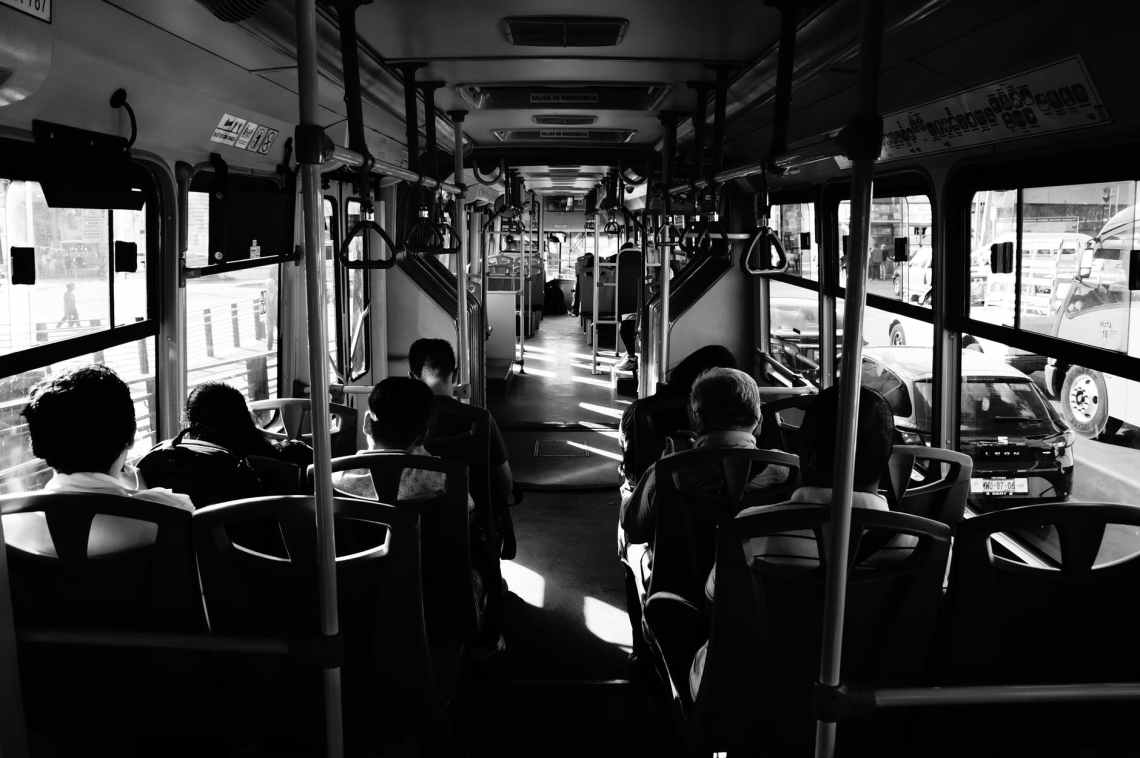 grayscale photo of people sitting inside a bus